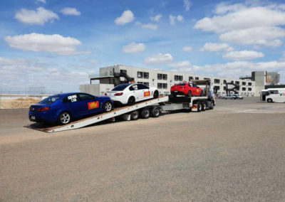 A heavy tow truck being loaded with three race cars